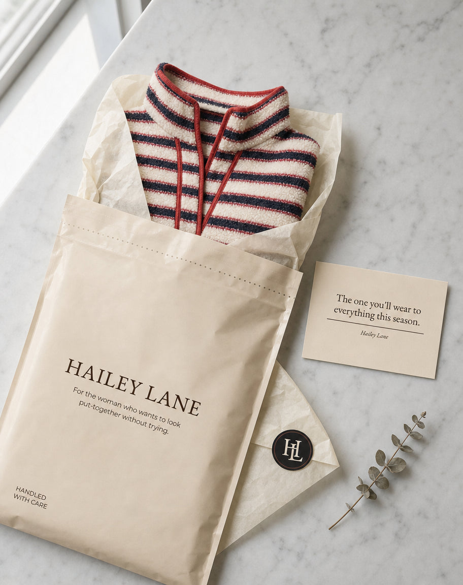Hailey Lane recycled mailer opened to tissue-wrapped knitwear beside a handwritten thank you card